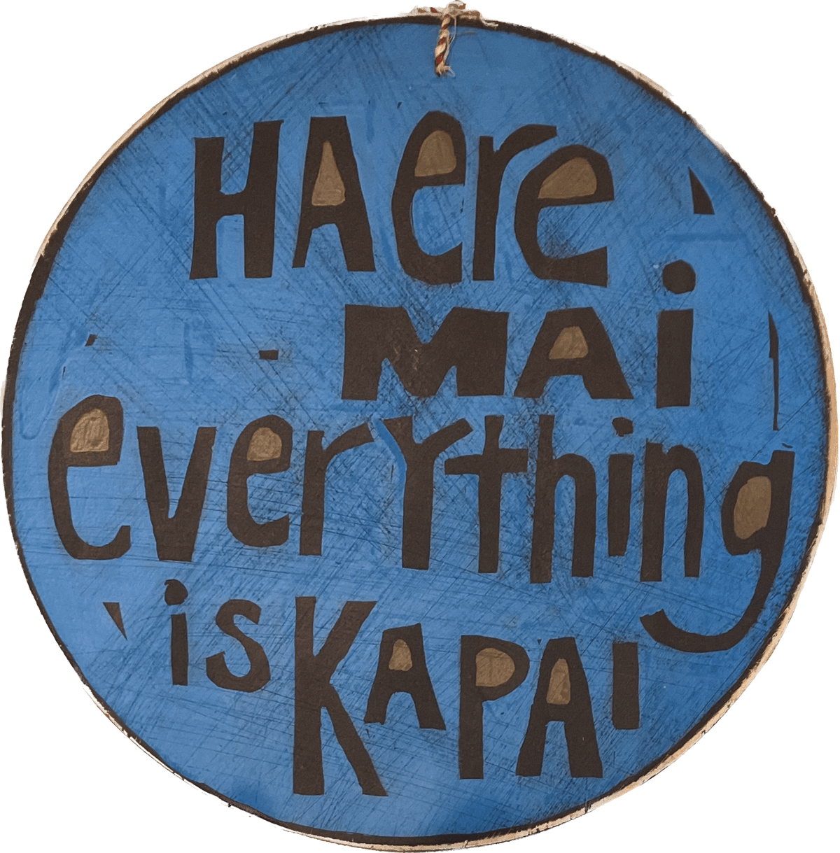A round piece of wall art with the words 'Haere mai everything is kapai' on it.