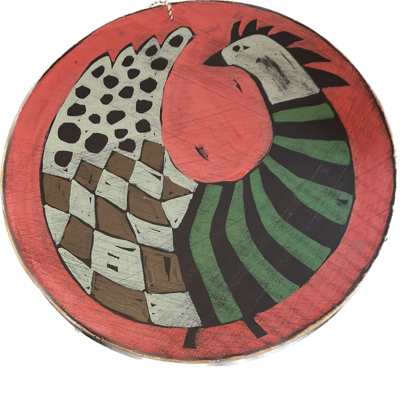 A round wooden piece of wall art with a painting of a bird on a red background.