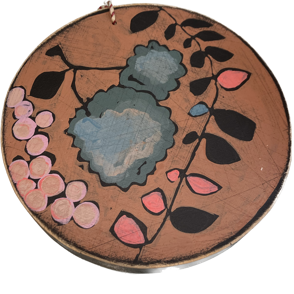 A round piece of wall art with floral paintings on it.