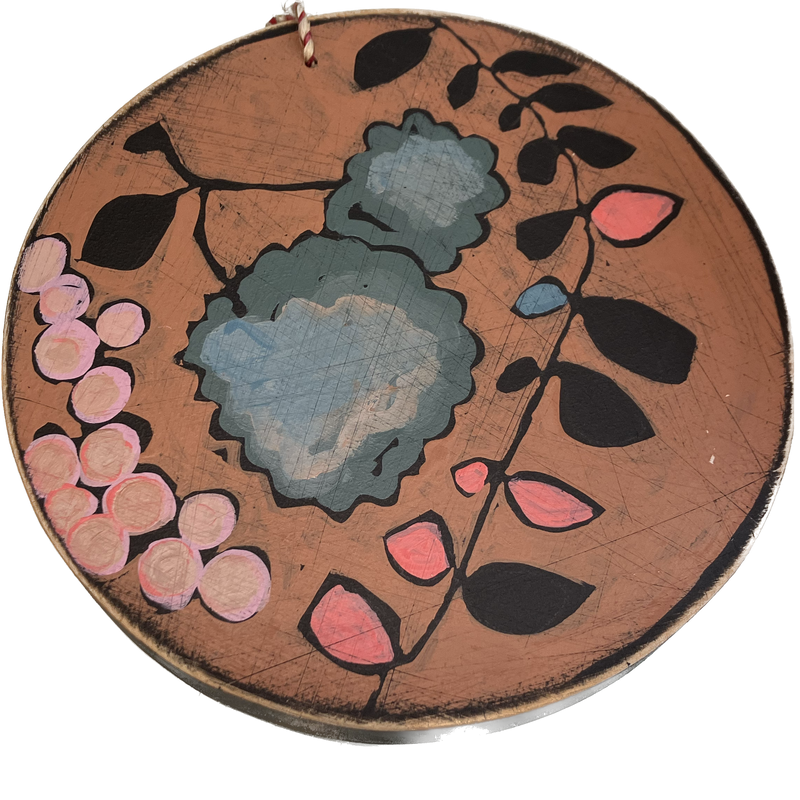 A round piece of wall art with floral paintings on it.